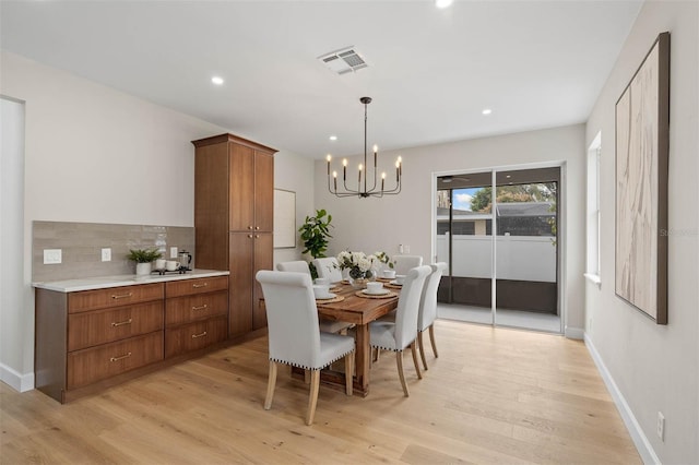 dining space featuring light wood-type flooring and an inviting chandelier