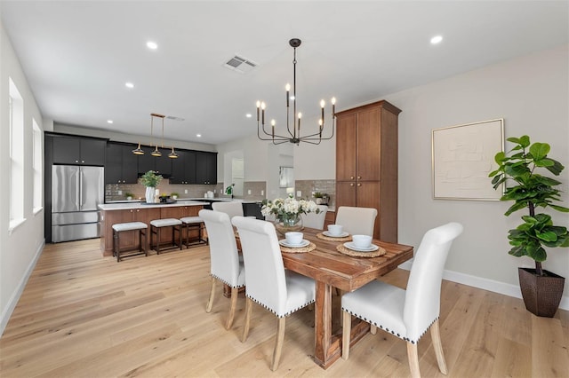 dining area with sink, light hardwood / wood-style floors, and a chandelier