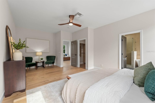 bedroom featuring ceiling fan, light wood-type flooring, a walk in closet, and ensuite bathroom