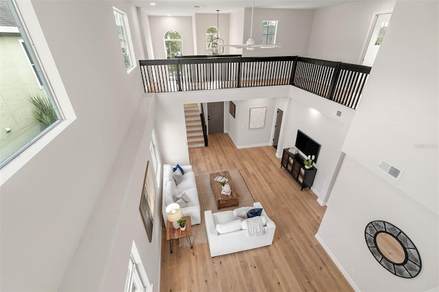 living room featuring ceiling fan, light wood-type flooring, and a high ceiling