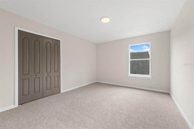 unfurnished bedroom with light carpet and a closet