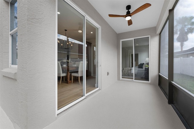 unfurnished sunroom featuring ceiling fan with notable chandelier