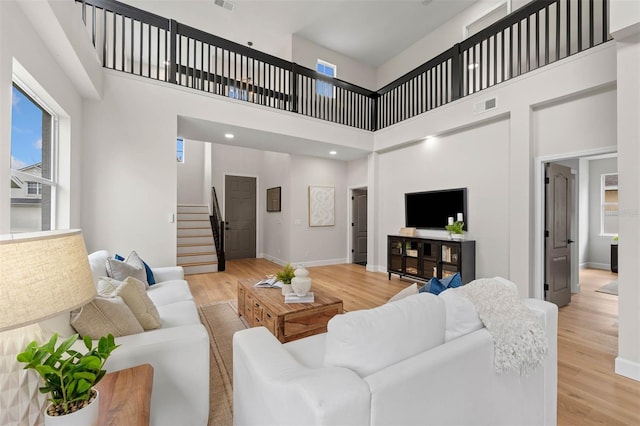 living room featuring light wood-type flooring and a high ceiling