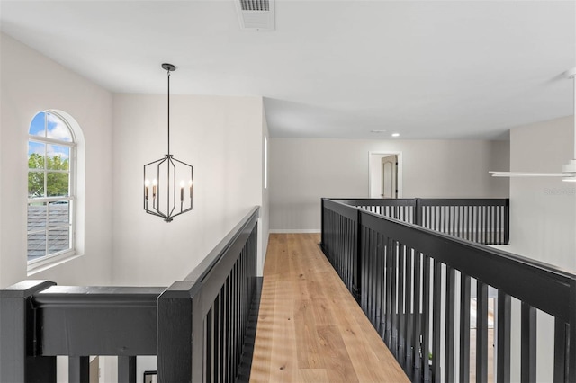 hallway with a notable chandelier and hardwood / wood-style floors