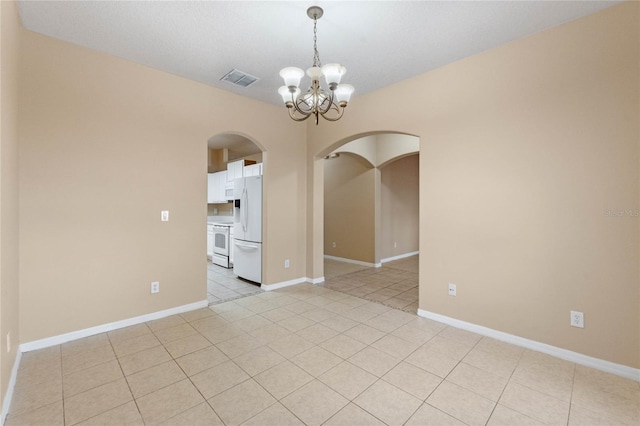 empty room featuring light tile patterned floors and a chandelier