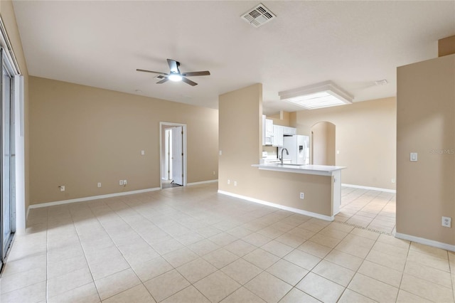 unfurnished living room featuring sink, light tile patterned floors, and ceiling fan