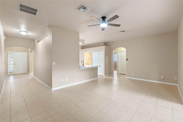 tiled empty room featuring ceiling fan, sink, and a textured ceiling