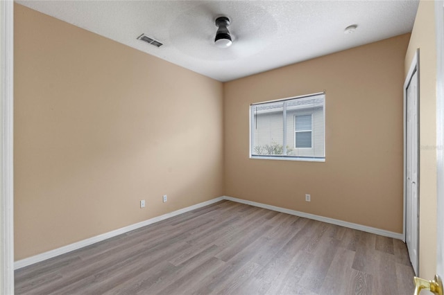 unfurnished bedroom featuring a closet, a textured ceiling, and light wood-type flooring