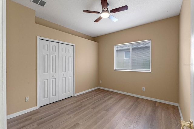 unfurnished bedroom featuring ceiling fan, a closet, and light wood-type flooring