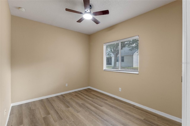 empty room with ceiling fan and light hardwood / wood-style flooring