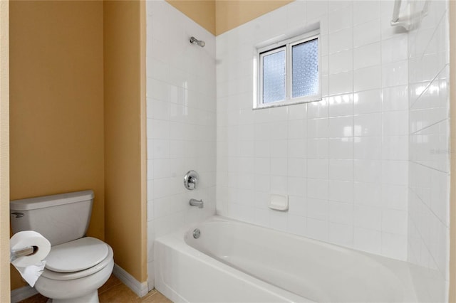 bathroom featuring tile patterned flooring, tiled shower / bath combo, and toilet