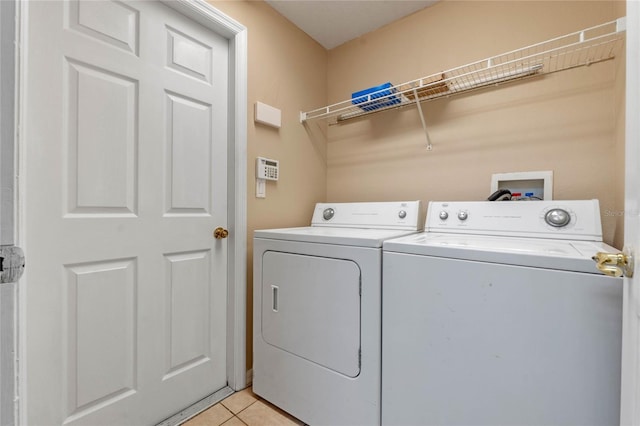 laundry room with light tile patterned floors and washer and clothes dryer