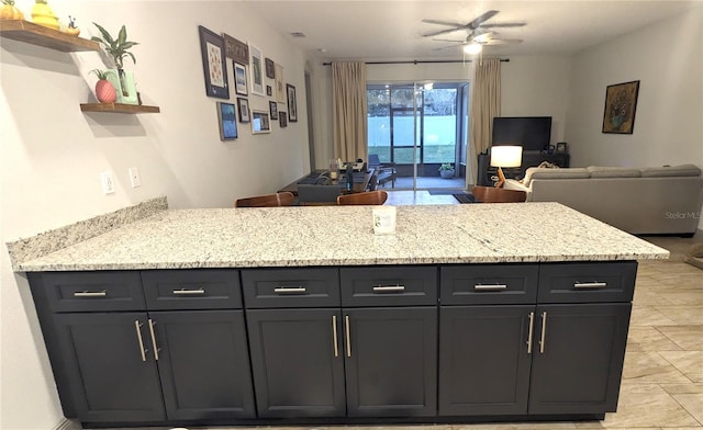 kitchen featuring light stone counters and ceiling fan