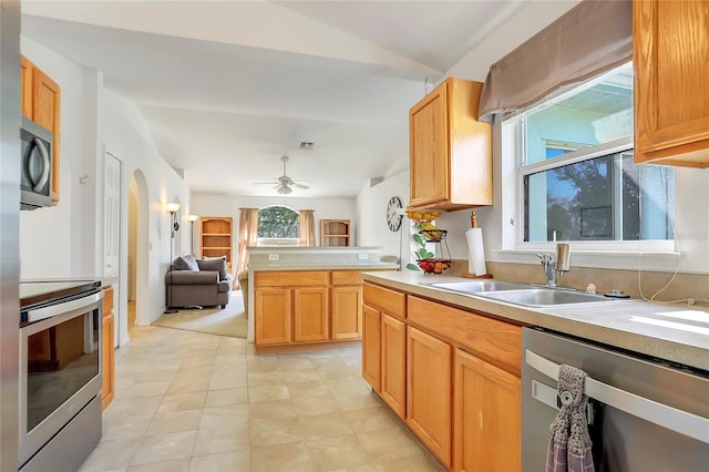 kitchen featuring stainless steel appliances, light countertops, a sink, and open floor plan