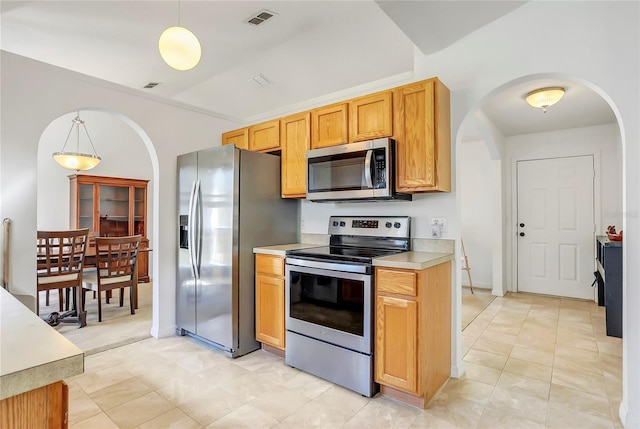 kitchen featuring arched walkways, light countertops, hanging light fixtures, visible vents, and appliances with stainless steel finishes