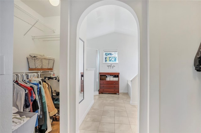 walk in closet featuring arched walkways, light tile patterned flooring, and lofted ceiling