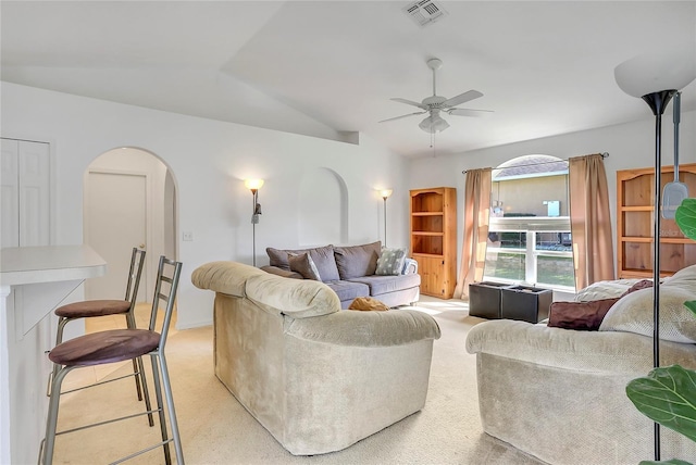 living room with arched walkways, ceiling fan, light colored carpet, visible vents, and vaulted ceiling