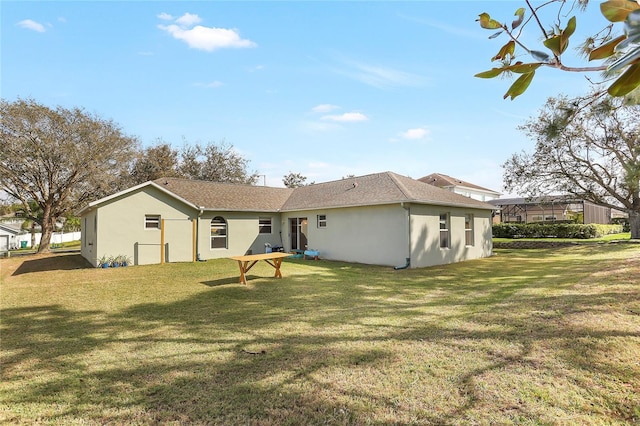 rear view of property featuring a yard and stucco siding