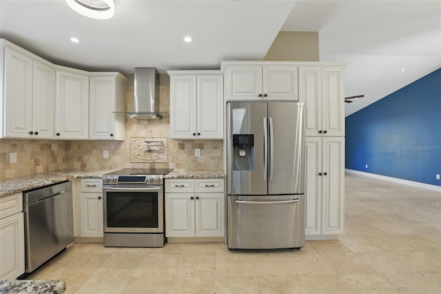 kitchen featuring decorative backsplash, light stone counters, wall chimney exhaust hood, and stainless steel appliances