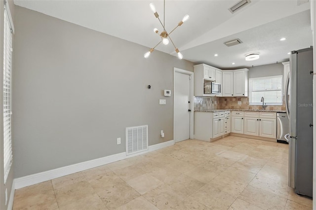 kitchen featuring decorative backsplash, visible vents, appliances with stainless steel finishes, and a sink