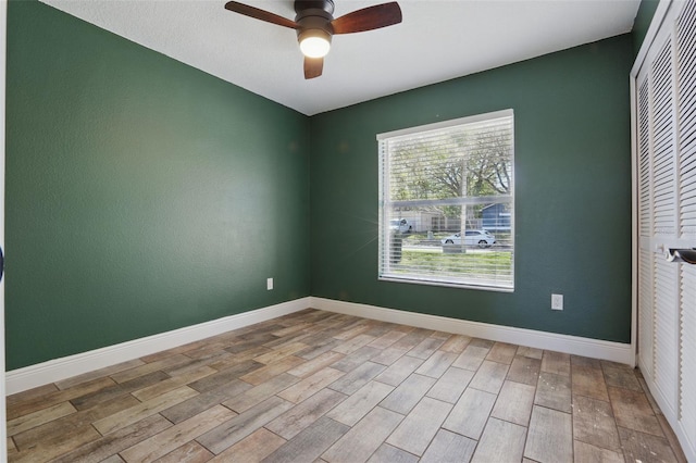 empty room featuring a ceiling fan, baseboards, and wood finished floors