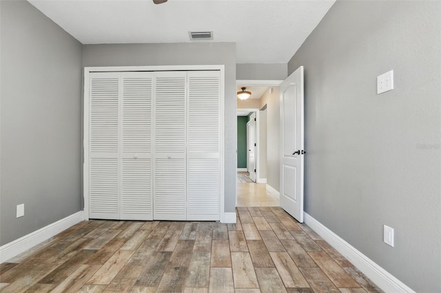 unfurnished bedroom featuring a closet, visible vents, baseboards, and wood finished floors