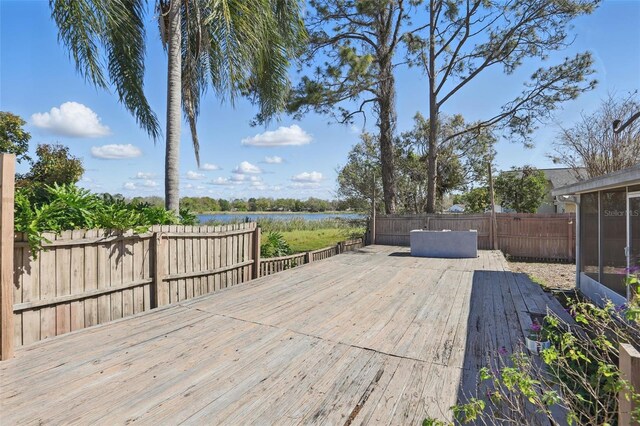 wooden deck with fence, a water view, and a sunroom