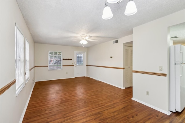 empty room with ceiling fan, plenty of natural light, and dark hardwood / wood-style flooring