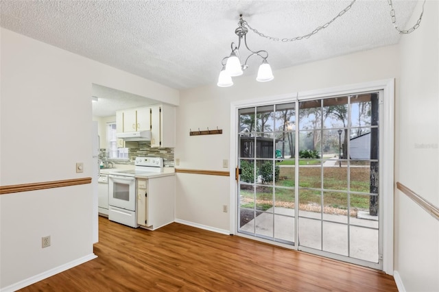 interior space featuring hanging light fixtures, light wood-type flooring, electric stove, decorative backsplash, and white cabinets