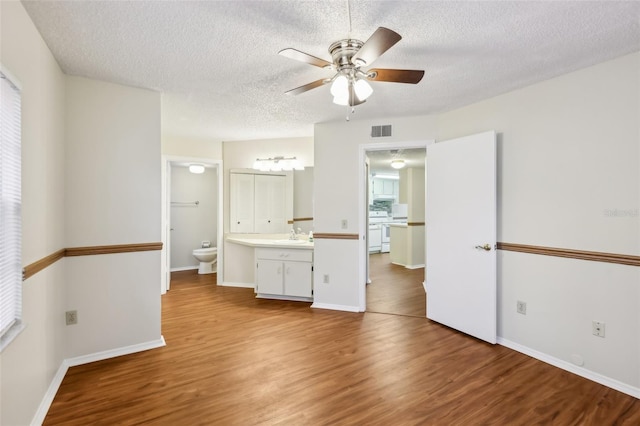 empty room with ceiling fan, sink, a textured ceiling, and light hardwood / wood-style flooring