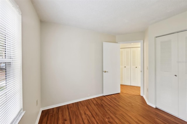 unfurnished bedroom featuring hardwood / wood-style floors, a textured ceiling, and a closet