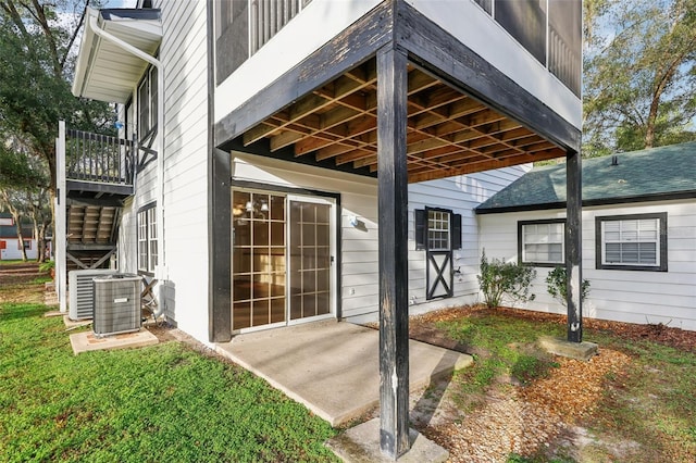 entrance to property featuring a lawn, central air condition unit, and a patio area