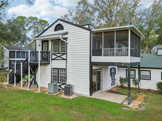 rear view of house with a sunroom, cooling unit, and a lawn