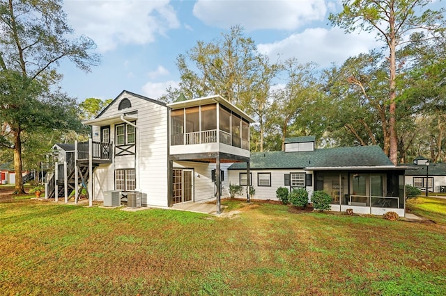 rear view of house with central AC, a yard, a patio area, and a sunroom