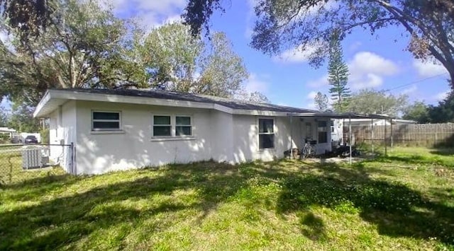 rear view of property featuring central AC unit and a lawn