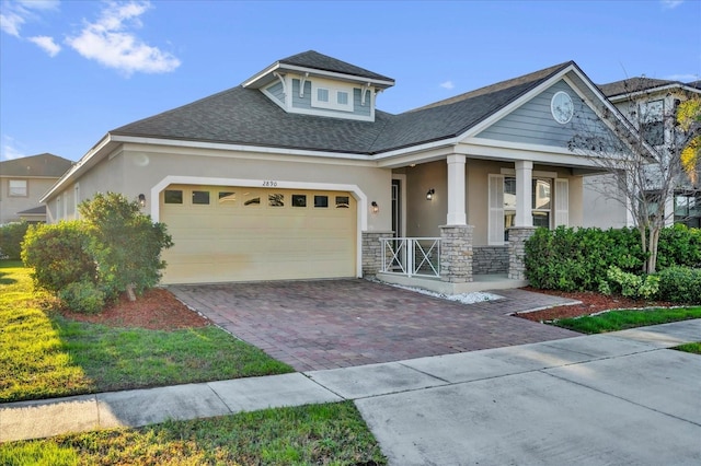 view of front of house with a garage, stone siding, decorative driveway, and stucco siding