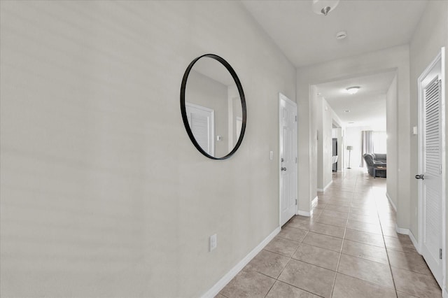 corridor featuring light tile patterned floors and baseboards