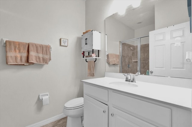 bathroom featuring toilet, a stall shower, vanity, tile patterned flooring, and baseboards