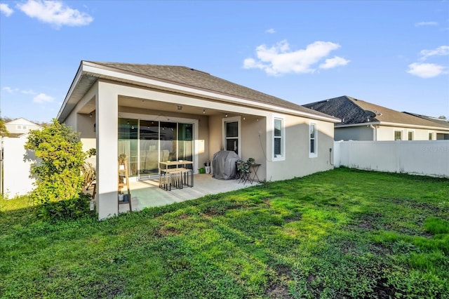 rear view of house with a yard, a patio area, fence, and stucco siding