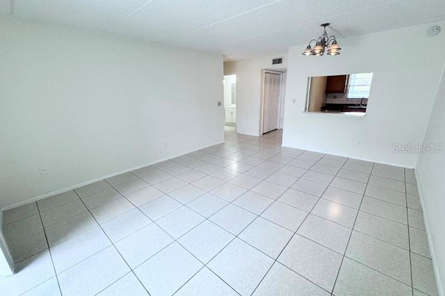 spare room featuring an inviting chandelier and light tile patterned flooring