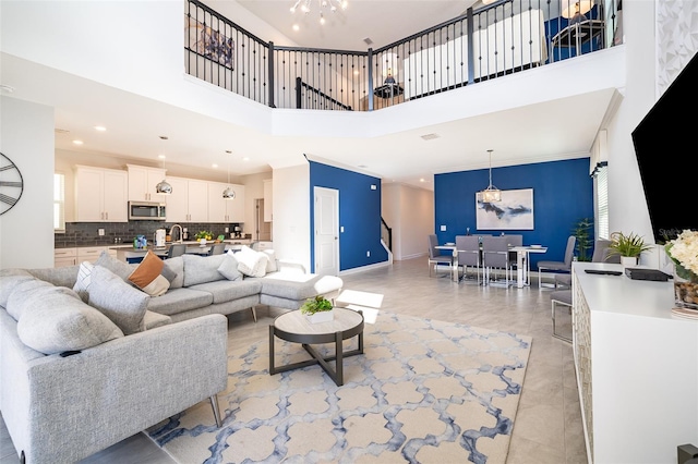 living room featuring a high ceiling, sink, and an inviting chandelier