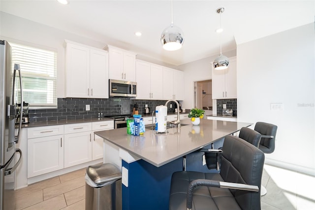 kitchen with white cabinetry, appliances with stainless steel finishes, a breakfast bar area, and hanging light fixtures