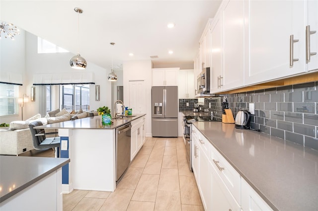 kitchen with sink, decorative light fixtures, white cabinets, stainless steel appliances, and backsplash