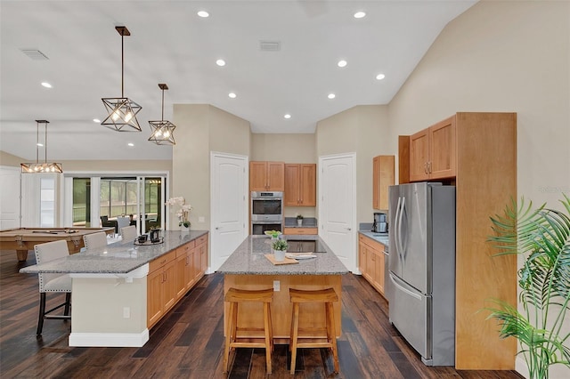 kitchen with appliances with stainless steel finishes, a breakfast bar area, a spacious island, and decorative light fixtures