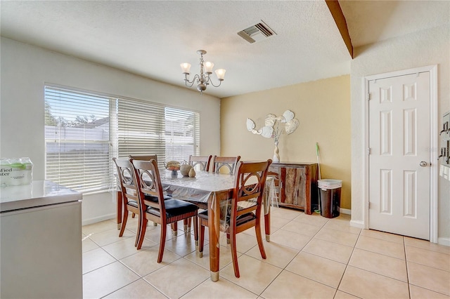 dining space featuring a notable chandelier, a textured ceiling, and light tile patterned flooring