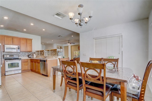 dining space with ceiling fan with notable chandelier, sink, and light tile patterned floors