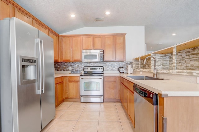 kitchen featuring light tile patterned flooring, vaulted ceiling, sink, backsplash, and stainless steel appliances