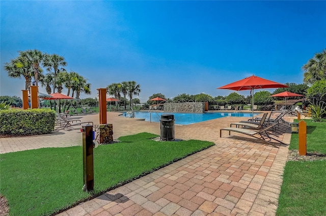 view of swimming pool with pool water feature, a patio area, and a lawn