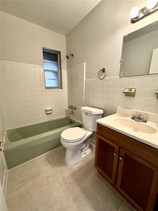 full bathroom with tile walls, tiled shower / bath combo, vanity, tile patterned floors, and toilet