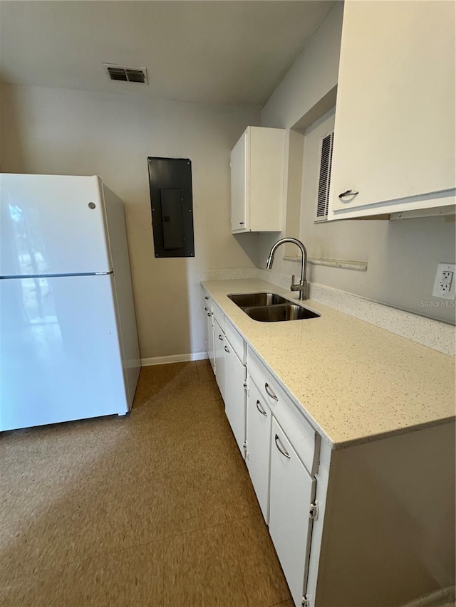 kitchen featuring sink, white cabinets, white refrigerator, electric panel, and light stone counters